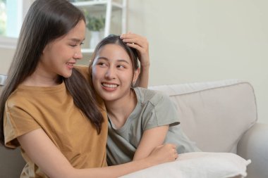 LGBT. Asyalı lezbiyen çift gülümsüyor ve evde sevgi gösteriyorlar. Genç Asyalı çift birbirlerine mutlu bir şekilde sarılıyorlar, aşıklar, homoseksüellik, eşcinsellik, özgürlük, ifadeler, ilişki.