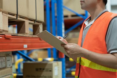 Asya 'daki erkek fabrika envanterini inceleyip kontrol ediyor, stok ürünlerini sayıyor. Lojistik ticaret nakliyesi, müşterilere teslimat. Denetleme, depo, depolama, fabrika, yönetme.