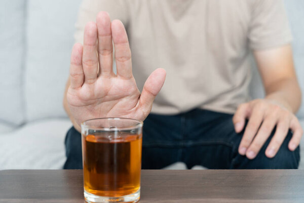 man refuses say no and avoid to drink an alcohol whiskey , stopping hand sign male, alcoholism treatment, alcohol addiction, quit booze, Stop Drinking Alcohol. Refuse Glass liquor, unhealthy, reject