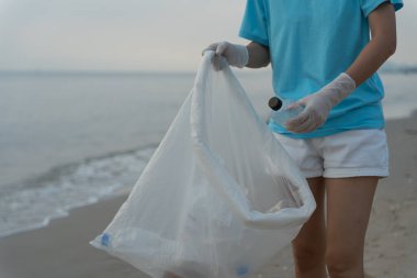 Okyanusu kurtar. Gönüllü olarak plajdaki çöpleri topluyor ve plastik şişeler suda yaşayan canlılara zarar gelmesini engelliyor. Dünya, Çevre, Yeşilci Gezegen, küresel ısınmayı azaltmak, Dünya 'yı kurtarmak