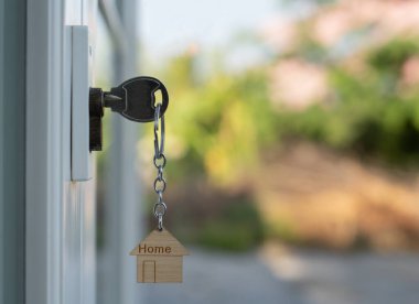 Landlord key for unlocking house is plugged into the door. Second hand house for rent and sale. keychain is blowing in the wind. mortgage for new home, buy, sell, renovate, investment, owner, estate