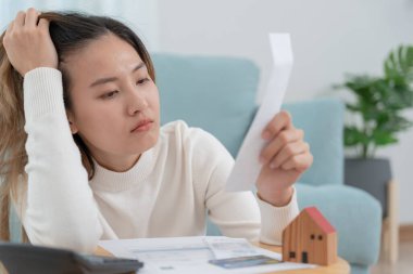 Borç evi, strese girmiş ve baş ağrısı çeken Asyalı kadın. Faturaları ya da faturaları ödenecek parası yok. Eksiklik, mali sorunlar, ipotek, kredi, iflas, iflas, yoksul, vadesi geçmiş cüzdan.