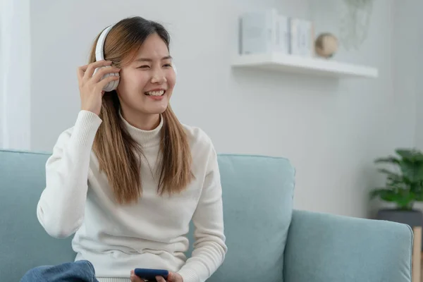 stock image Joyful young Asian women in wireless headphones sitting and enjoy music, having fun, listening to music, raising his arm, dancing to favorite song, enjoying cool soundtrack, happy life, recreation