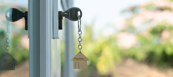 stock image Landlord key for unlocking house is plugged into the door. Second hand house for rent and sale. keychain is blowing in the wind. mortgage for new home, buy, sell, renovate, investment, owner, estate