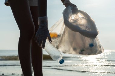 Okyanusu kurtar. Gönüllü olarak plajdaki çöpleri topluyor ve plastik şişeler suda yaşayan canlılara zarar gelmesini engelliyor. Dünya, Çevre, Yeşilci Gezegen, küresel ısınmayı azaltmak, Dünya 'yı kurtarmak