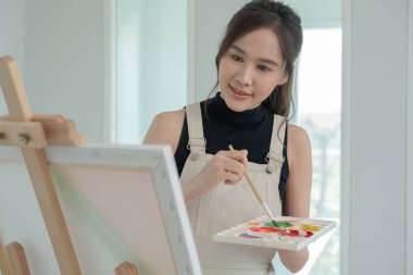 beautiful female hobbies about artist and use paintbrush in abstract art for create masterpiece. painter paint with watercolors or oil in studio house. enjoy painting as hobby, recreation, inspiration