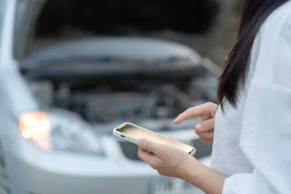 stock image breakdown, broken car, repair. Woman uses mobile phone check insurance premiums through application due to car accident . Find garage to get car fixed during country tour, waiting for help, emergency.