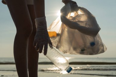 Su tasarrufu. Gönüllü olarak plajdaki çöpleri topluyor ve plastik şişeler suda yaşayan canlılara zarar gelmesini engelliyor. Dünya, Çevre, Yeşilci Gezegen, küresel ısınmayı azaltmak, Dünya 'yı kurtarmak