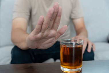 Adam hayır demeyi reddediyor ve alkollü viski içmekten kaçınıyor, el işareti yapan erkek, alkolizm tedavisi, alkol bağımlılığı, içkiyi bırakmak, alkol içmeyi bırakmak. İçkiyi reddet, sağlıksız, reddedilmiş
