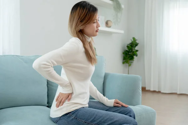 stock image Asia beautiful woman holding her lower back while and suffer from unbearable pain health and problems, chronic back pain, backache in office syndrome, scoliosis, herniated disc, muscle inflammation