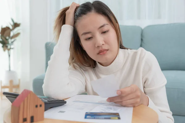 Debt house, Stressed and headache asian woman with large bills or invoices no money to pay, shortage, Financial problems, mortgage, loan, bankruptcy, bankrupt, poor, empty wallet, overdue