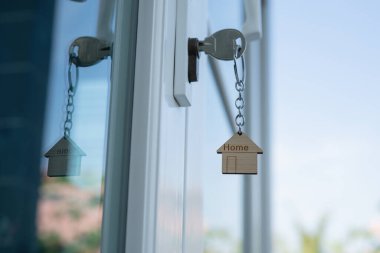 Landlord key for unlocking house is plugged into the door. Second hand house for rent and sale. keychain is blowing in the wind. mortgage for new home, buy, sell, renovate, investment, owner, estate
