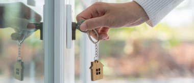 Landlord key for unlocking house is plugged into the door. Second hand house for rent and sale. keychain is blowing in the wind. mortgage for new home, buy, sell, renovate, investment, owner, estate