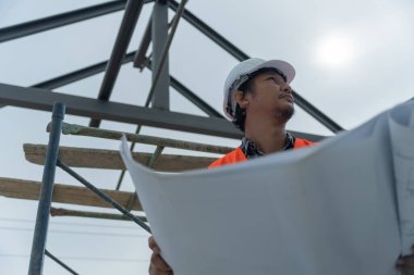 Mühendisler ya da müfettişler inşaat planlarını ellerinde tutuyorlar. Sivil projeye başlamadan önce müteahhit teftişi çizimi. İnşaat projesi planlama, danışmanlık ve mimariyi hazırlayın.