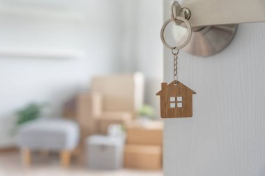 Moving house, relocation. The key was inserted into the door of the new house, inside the room was a cardboard box containing personal belongings and furniture. move in the apartment or condominium