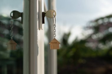 Landlord key for unlocking house is plugged into the door. Second hand house for rent and sale. keychain is blowing in the wind. mortgage for new home, buy, sell, renovate, investment, owner, estat