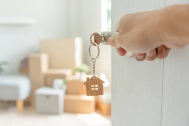 Moving house, relocation. The key was inserted into the door of the new house, inside the room was a cardboard box containing personal belongings and furniture. move in the apartment or condominium