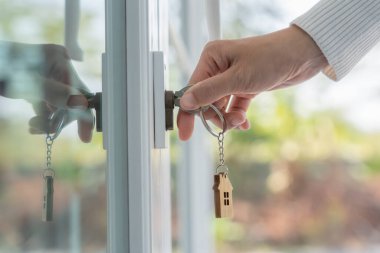 Landlord key for unlocking house is plugged into the door. Second hand house for rent and sale. keychain is blowing in the wind. mortgage for new home, buy, sell, renovate, investment, owner, estat