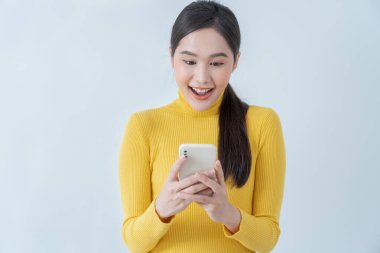 Asian beautiful woman exited surprise face expression . female feels shocked with the phone. exciting smile and happy adorable rejoices. Very enjoy and fun relax time. wow, girl holding smartphone.