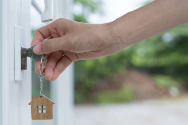 Landlord key for unlocking house is plugged into the door. Second hand house for rent and sale. keychain is blowing in the wind. mortgage for new home, buy, sell, renovate, investment, owner, estate