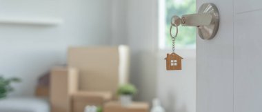 Moving house, relocation. The key was inserted into the door of the new house, inside the room was a cardboard box containing personal belongings and furniture. move in the apartment or condominium