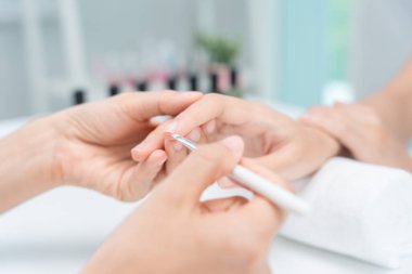 Kadın, güzellik merkezinde profesyonel güzellik manikürü ile bakım hizmeti alıyor. Güzellik salonunda jöle tedavisi için tırnak törpüsü kullanın. Manikürcü, çivi müşterisini güzelleştirir. vücut bakımı spa tedavisi