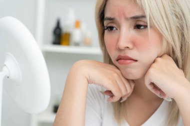 Genç Asyalı kadın, yüz dermatolojisi ve kozmetik ürünlerinde steroidlere alerjisi olduğu için endişeli. Hassas cilt, güneş yanığı, sivilce, kimyasallara alerjisi, yüzünde kızarıklık. cilt sorunları 