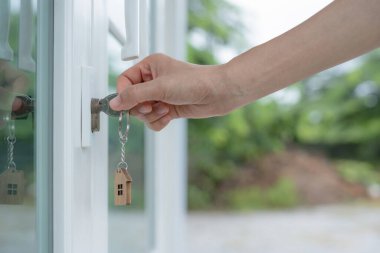 Landlord key for unlocking house is plugged into the door. Second hand house for rent and sale. keychain is blowing in the wind. mortgage for new home, buy, sell, renovate, investment, owner, estate