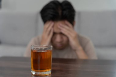 Depresyondaki genç Asyalı adam evde yalnız başına viski içmenin kötü hissettirdiğini vurguladı alkol içmek sorunlu içki, alkolizm, hayat ve aile sorunlarından muzdarip.