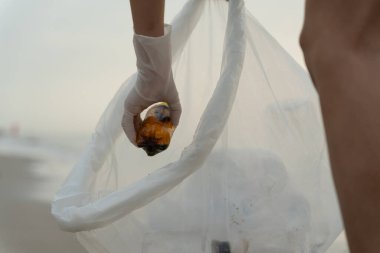 Su tasarrufu. Gönüllü olarak plajdaki çöpleri topluyor ve plastik şişeler suda yaşayan canlılara zarar gelmesini engelliyor. Dünya, Çevre, Yeşilci Gezegen, küresel ısınmayı azaltmak, Dünya 'yı kurtarmak