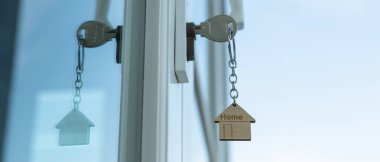 Landlord key for unlocking house is plugged into the door. Second hand house for rent and sale. keychain is blowing in the wind. mortgage for new home, buy, sell, renovate, investment, owner, estate