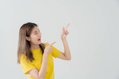 Portrait asian beautiful girl pointing blank space isolated background. Happy woman pointing on something. young female standing pointing finger sideways, billboard, introduction, advertisement, space