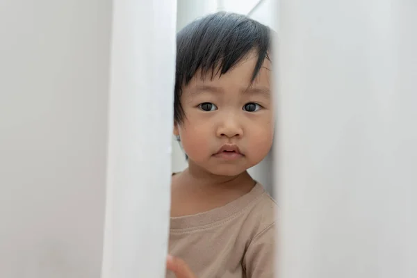 stock image little asian children kid , playing hide and seek standing next a wall house, Adorable child having fun in the home. happy family have fun with kids, activity, learning