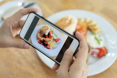 Restoran sahibi masadaki yemeklerin fotoğrafını çekiyor ve web sitesine yüklemek için akıllı telefon kullanıyor. Çevrimiçi gıda dağıtımı, sipariş servisi, nüfuz, gözden geçirme, sosyal medya, paylaşım, pazarlama, faiz.