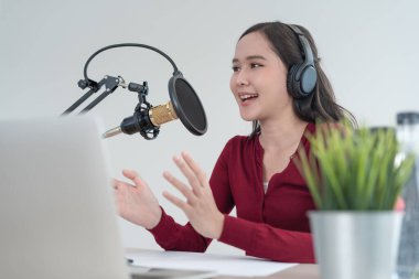 Asyalı kadın bir radyo yayın istasyonunda cesaretlendirmek için konuşuyor. Güzel bir kadın radyo programını organize etti. Radyo, podcast, canlı buhar, eğlence, dinle, teknoloji, müzik, hoparlör