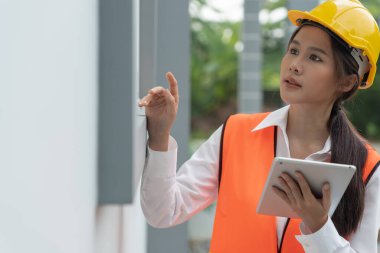 Müfettiş ya da mühendis, tablet kullanarak yeni ev inşaatını ve kalite güvencesini denetliyor. Mühendisler, mimarlar ya da irtibat görevlileri ev sahibine teslim etmeden önce evi inşa etmek için çalışıyorlar.