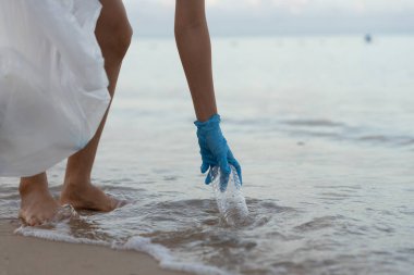 Su tasarrufu. Gönüllü olarak plajdaki çöpleri topluyor ve plastik şişeler suda yaşayan canlılara zarar gelmesini engelliyor. Dünya, Çevre, Yeşilci Gezegen, küresel ısınmayı azaltmak, Dünya 'yı kurtarmak