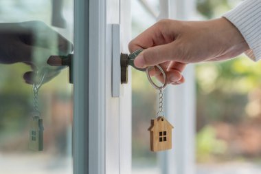 Landlord key for unlocking house is plugged into the door. Second hand house for rent and sale. keychain is blowing in the wind. mortgage for new home, buy, sell, renovate, investment, owner, estate