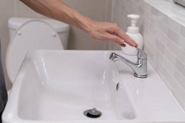 Su tasarrufu. Adam çevreyi korumak için tuvaletteki suyu kapatıp duruyor. Yeşillenen gezegen, küresel ısınmayı azalt Dünya 'yı, yaşamı, geleceği, risk enerjisini, krizi, su gününü kurtar.