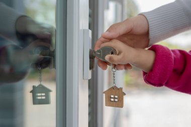 Evin kilidini açmak için ev sahibi anahtarı kapıya takılı. Kira ve satış için ikinci el ev. Sahibi yeni ev, satın al, sat, yenile, yatırım, sahip, mülk