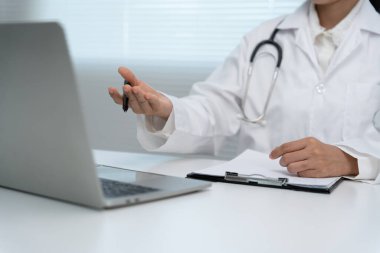 Telemedikal. Doktorlar, hastaların bir röportaj videosunun kaydını tutarlar. Asyalı doktor hastaları telekomünikasyon yoluyla tedavi ederken hastalığı tarif ediyor. Sağlık teknolojisi