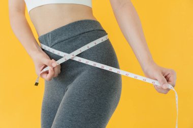 Diyet ve diyet. Güzel, ince kadın vücut ölçüsü. Spor elbiseli bir kadın sağlıklı yaşam için kilo verme hedefine, zayıflığa, ince belliye, beslenme uzmanına ulaşır..