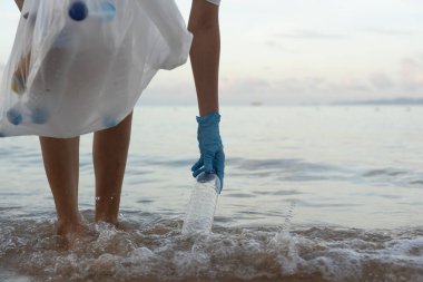 Su tasarrufu. Gönüllü olarak plajdaki çöpleri topluyor ve plastik şişeler suda yaşayan canlılara zarar gelmesini engelliyor. Dünya, Çevre, Yeşilci Gezegen, küresel ısınmayı azaltmak, Dünya 'yı kurtarmak