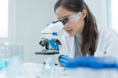 Bilimadamı ileri bilimsel laboratuvarda biyokimyasal örnekleri analiz ediyor. Tıbbi profesyonel kullanım mikroskobu virüsün mikrobiyolojik gelişimini gösteriyor. Fen laboratuvarında biyoteknoloji araştırması.