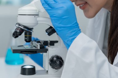 Bilimadamı ileri bilimsel laboratuvarda biyokimyasal örnekleri analiz ediyor. Tıbbi profesyonel kullanım mikroskobu virüsün mikrobiyolojik gelişimini gösteriyor. Fen laboratuvarında biyoteknoloji araştırması.