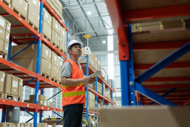 Asian male factory manager inspect goods in warehouse or inventory and check stock product. Transport logistic business shipping, delivery to customers. inspection, storehouse, storage, factory