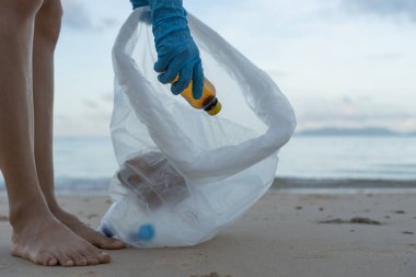 Su tasarrufu. Gönüllü olarak plajdaki çöpleri topluyor ve plastik şişeler suda yaşayan canlılara zarar gelmesini engelliyor. Dünya, Çevre, Yeşilci Gezegen, küresel ısınmayı azaltmak, Dünya 'yı kurtarmak