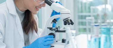 Bilimadamı ileri bilimsel laboratuvarda biyokimyasal örnekleri analiz ediyor. Tıbbi profesyonel kullanım mikroskobu virüsün mikrobiyolojik gelişimini gösteriyor. Fen laboratuvarında biyoteknoloji araştırması.