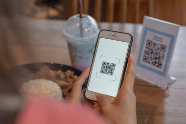 Woman use smartphone to scan QR code to pay in cafe restaurant with a digital payment without cash. Choose menu and order accumulate discount. E wallet, technology, pay online, credit card, bank app.