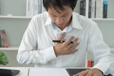 Göğüs kafesinde kalp krizi belirtileri var. Asyalı bir adamın göğüs ağrısı var. Kalp rahatsızlığı, sızıntı, genişleme, kalp büyümesi, göğsüne acı veren bir ifadeyle bastırma.